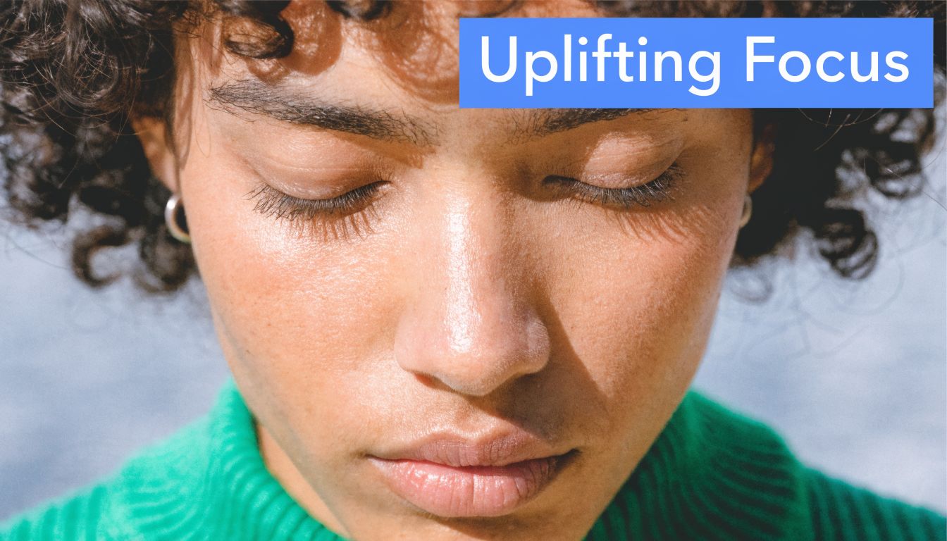 A close-up of a person with curly hair and closed eyes wearing a vibrant green sweater.