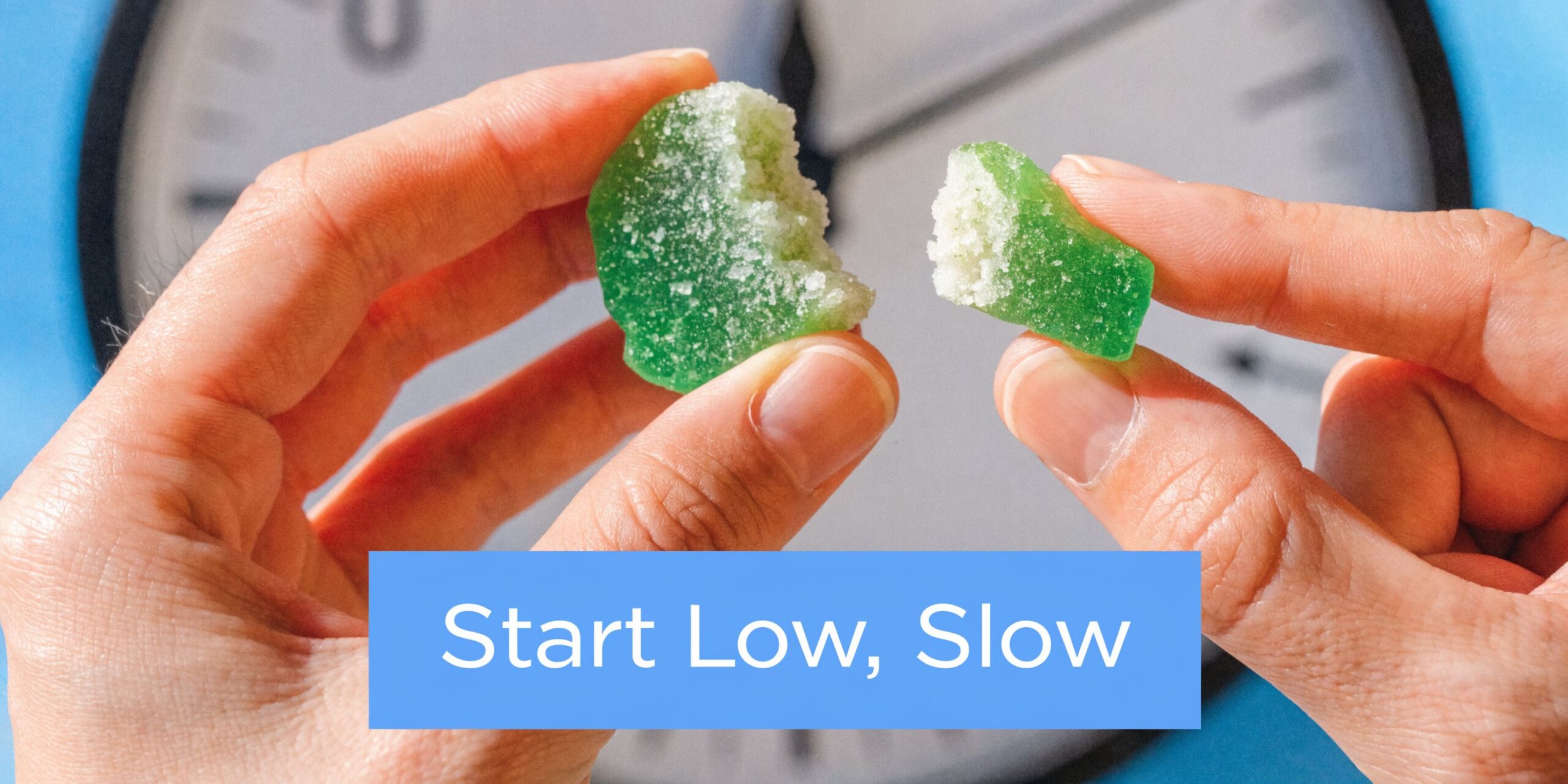 A person breaking a green gummy candy in half in front of a clock, representing slow consumption.